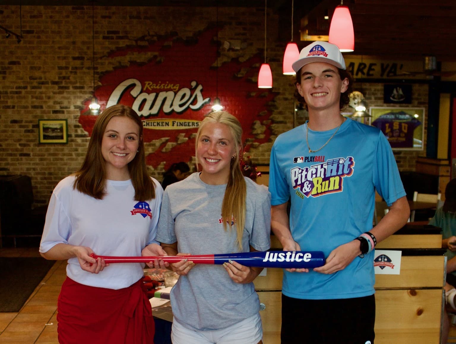 A group of teens holding a baseball bat that has the word "Justice" printed on the barrel