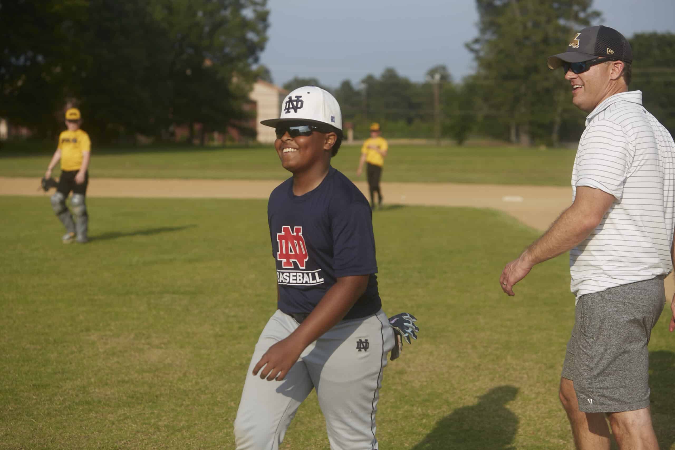 A coach and a young player laughing together on Justice Field.