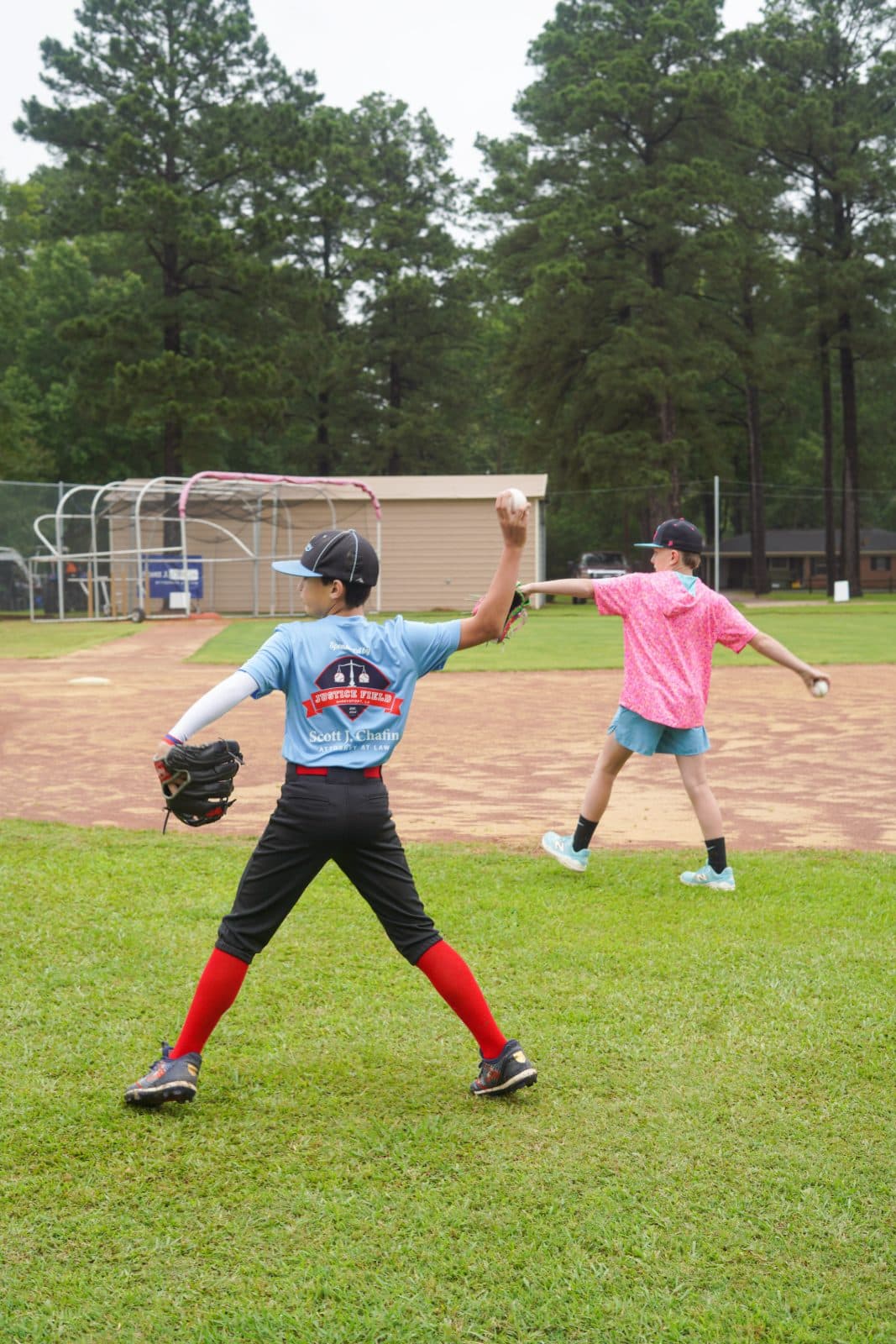 Two young players warming up and throwing on the field.