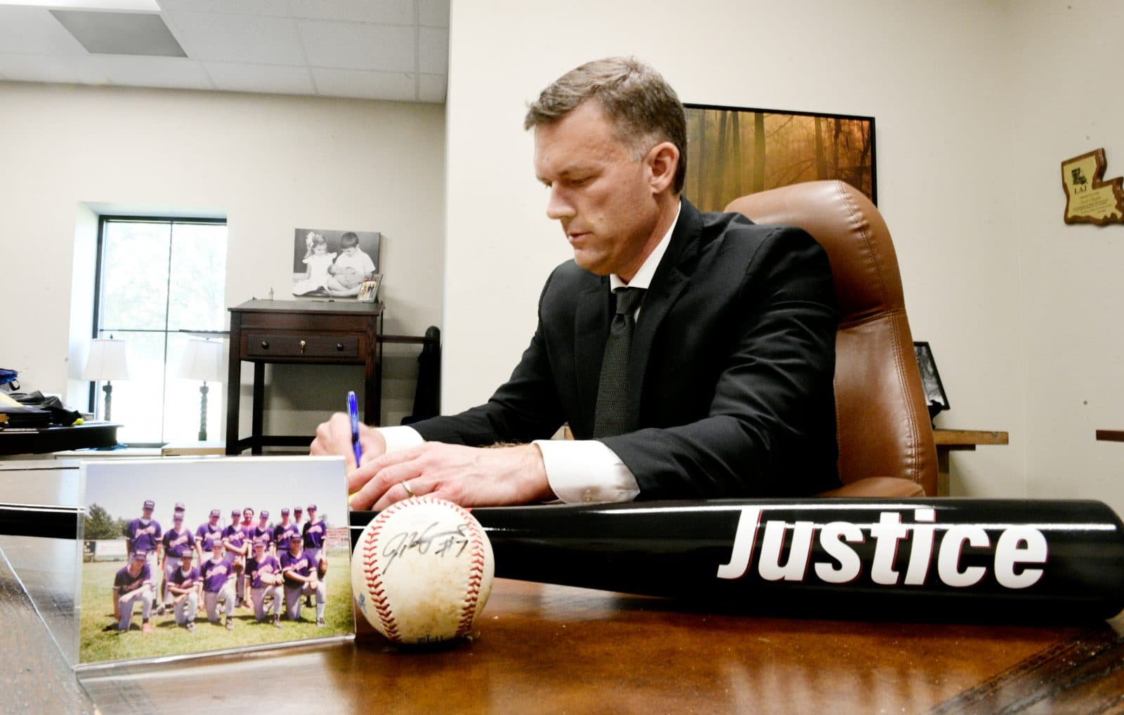 Scott Chafin at his Shreveport law office desk with the Justice bat, a baseball, and his old team photo.