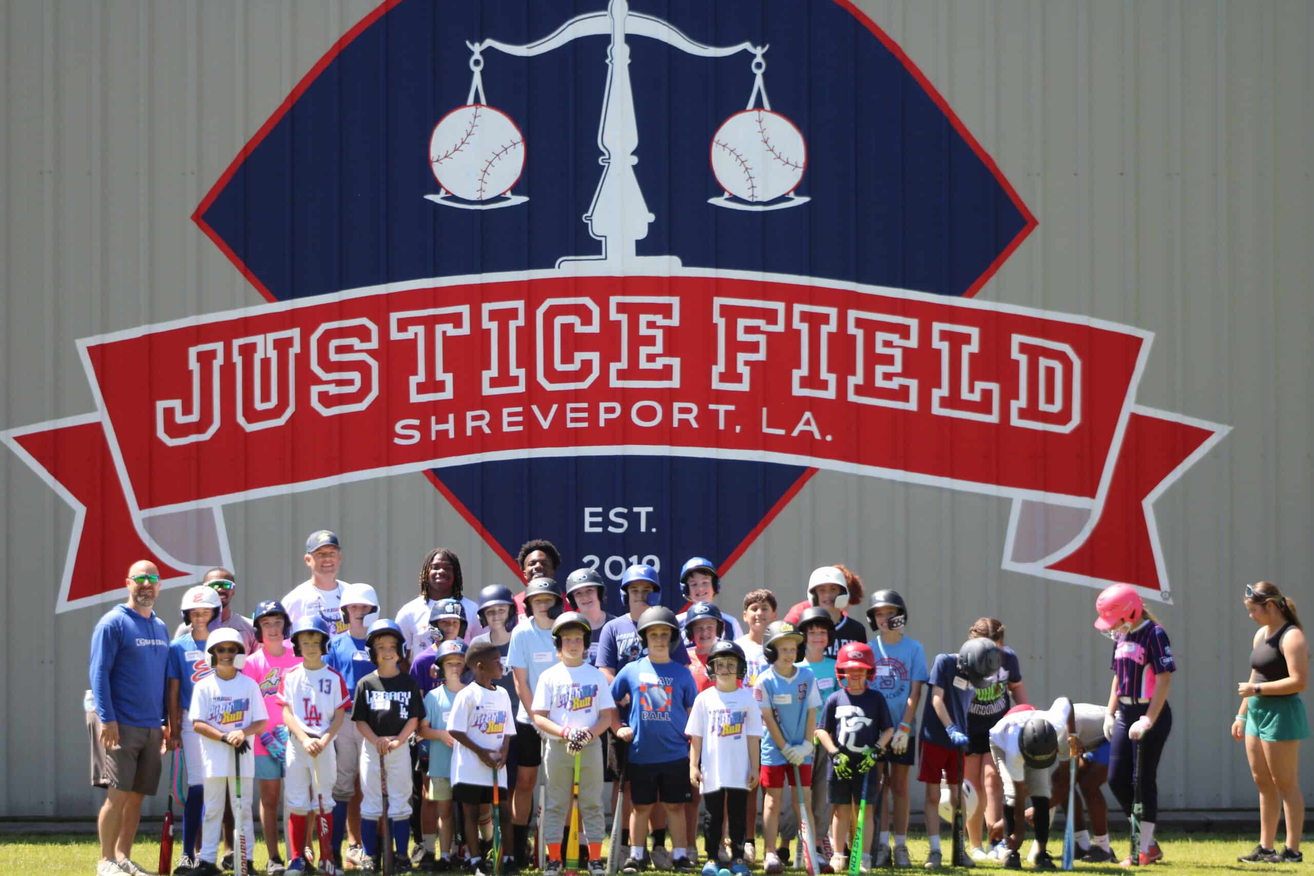 A large group of campers gathered in front of the painted Justice Field mural.